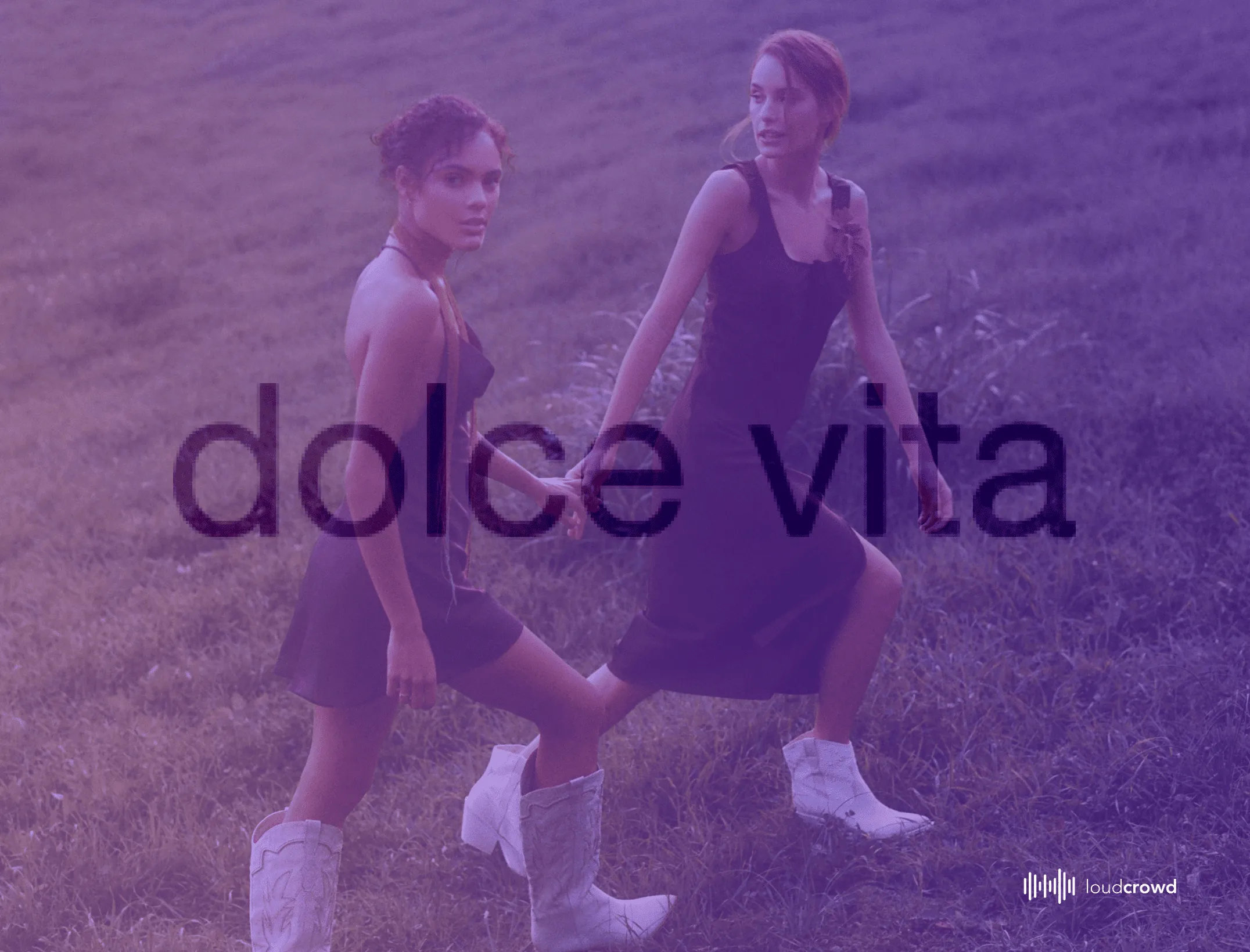 Two women in dresses and white boots walking through a field behind the Dolce Vita wordmark